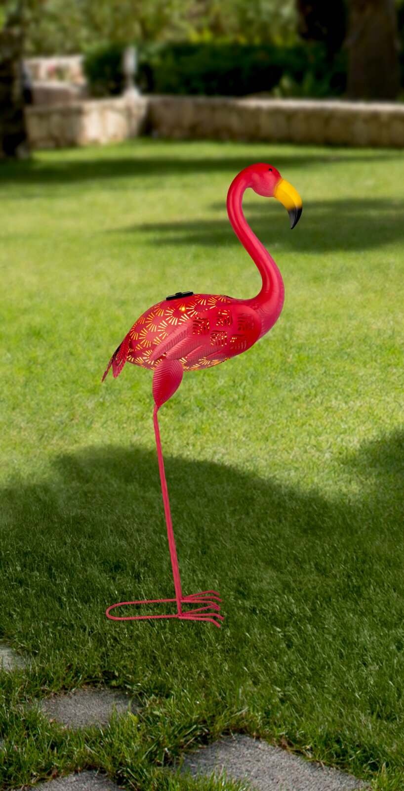 Zonne-lamp in de vorm van een roze flamingo, zijaanzicht op een grasveld