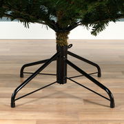 Nahaufnahme des unteren Teils eines künstlichen Weihnachtsbaums mit stabilem Metallständer auf Holzfußboden.