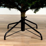 Nahaufnahme des unteren Teils eines künstlichen Weihnachtsbaums mit stabilem Metallständer auf Holzfußboden.