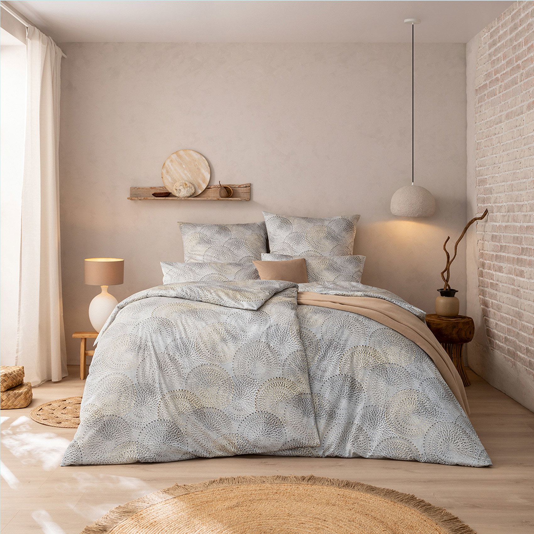 Modern eingerichtetes Schlafzimmer mit großem Doppelbett, Bettwäsche in Hellgrau mit kreisförmigem Muster.