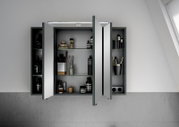 Moderner Spiegelschrank mit geöffneter Tür, gefüllt mit Pflegeprodukten und Accessoires, aus frontaler Perspektive.