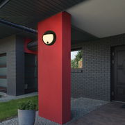 Moderne Akku-Außenwandleuchte an einer roten Wand, seitliche Perspektive