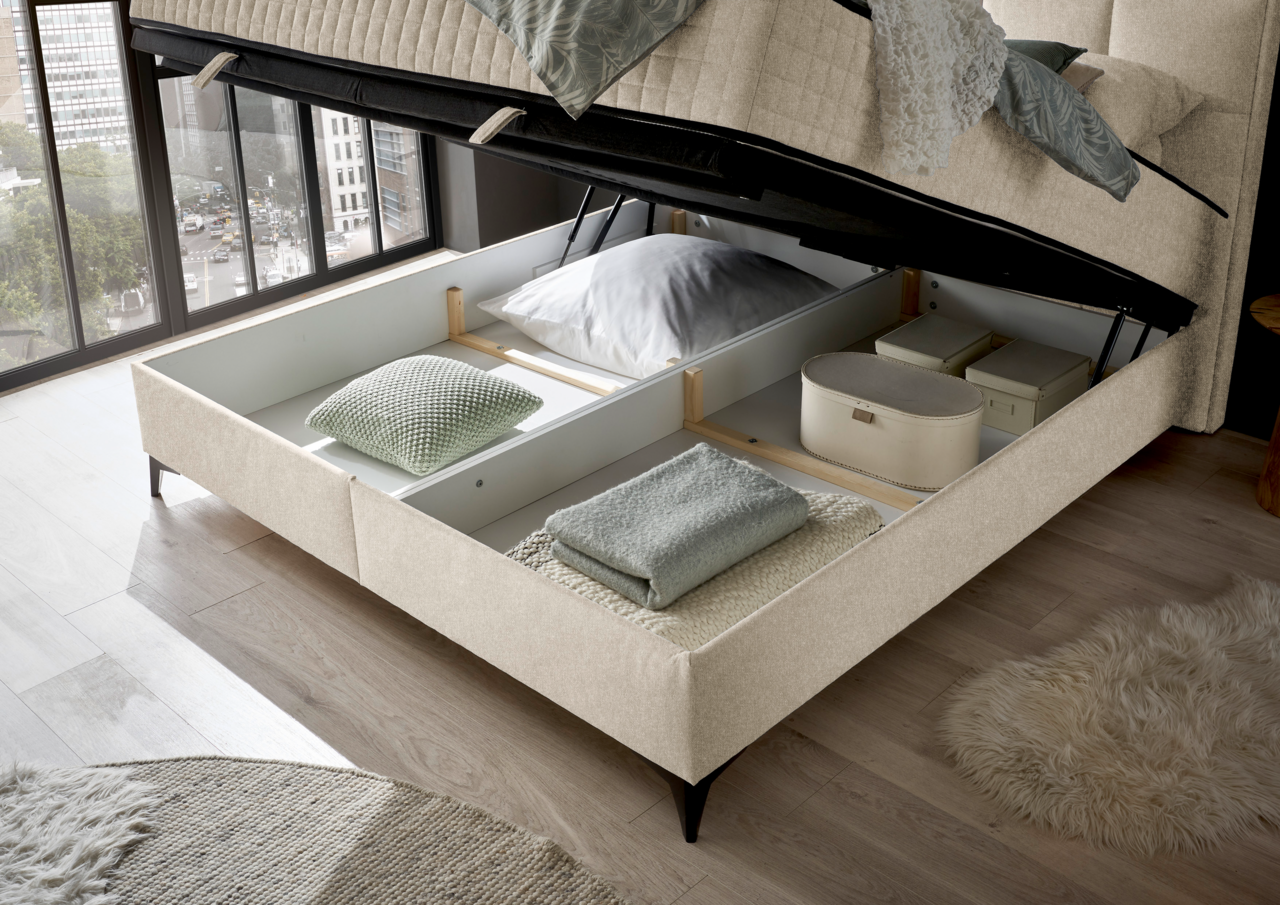 Boxbett mit geöffnetem Stauraum, von oben fotografiert, zeigt Kissen und Decken im Inneren.