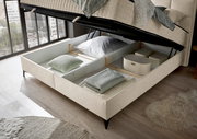 Boxbett mit geöffnetem Stauraum, von oben fotografiert, zeigt Kissen und Decken im Inneren.