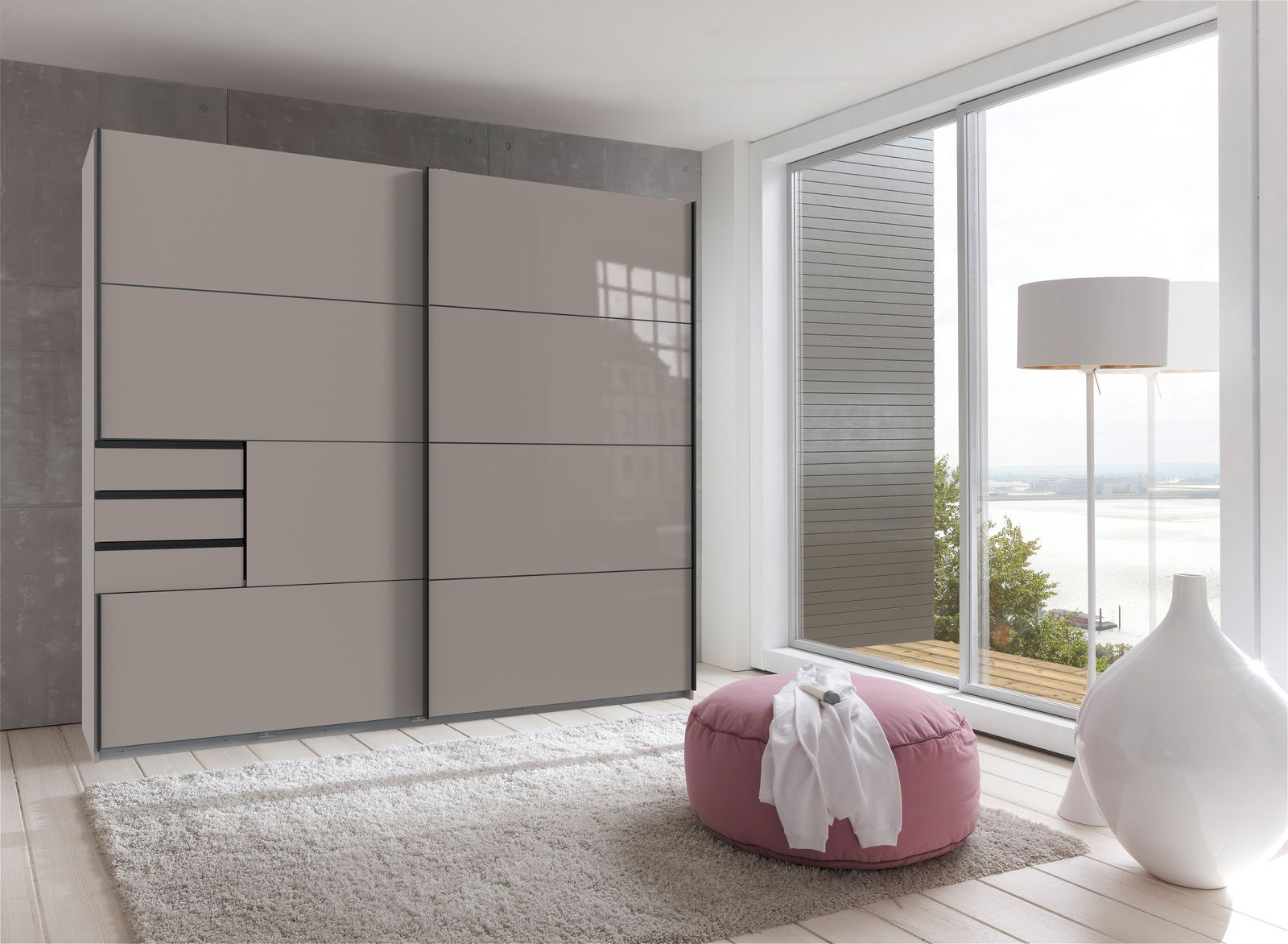 Moderner Schwebetürenschrank mit zwei Türen in einem hellen Raum mit Blick auf eine Terrasse. Perspektive von vorne links.