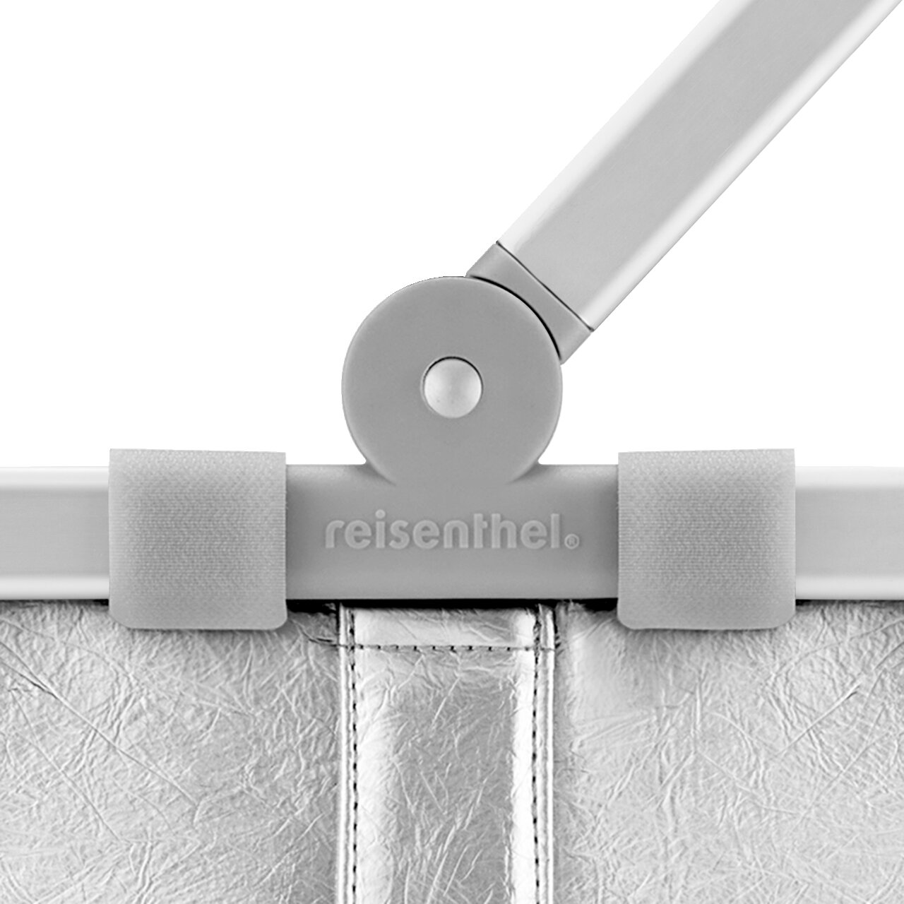 Detailaufnahme aus Frontansicht: Scharnier und Griffbefestigung einer silbernen reisenthel Tasche mit Klettlaschen und geprägtem Logo