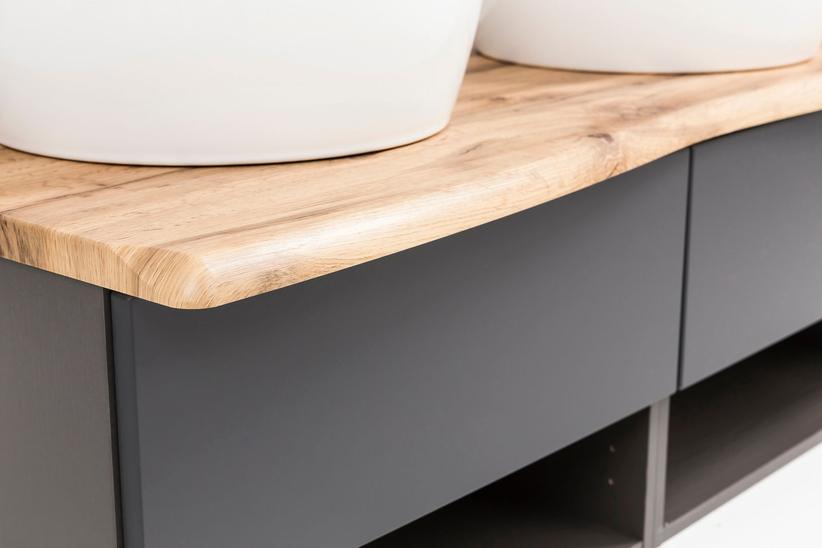 Nahaufnahme eines Waschtisch-Sets mit einer eleganten Holzoberfläche und modernen, dunklen Schubladenfronten, seitliche Perspektive.