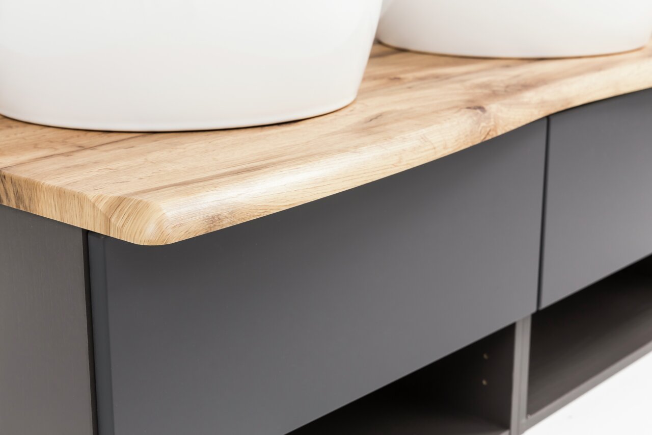 Nahaufnahme eines Waschtisch-Sets mit einer eleganten Holzoberfläche und modernen, dunklen Schubladenfronten, seitliche Perspektive.