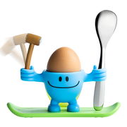 Blauer Eierbecher McEgg in Form einer Figur mit einem Löffel und einem Hammer, auf einem grünen Sockel stehend, frontal abgebildet.