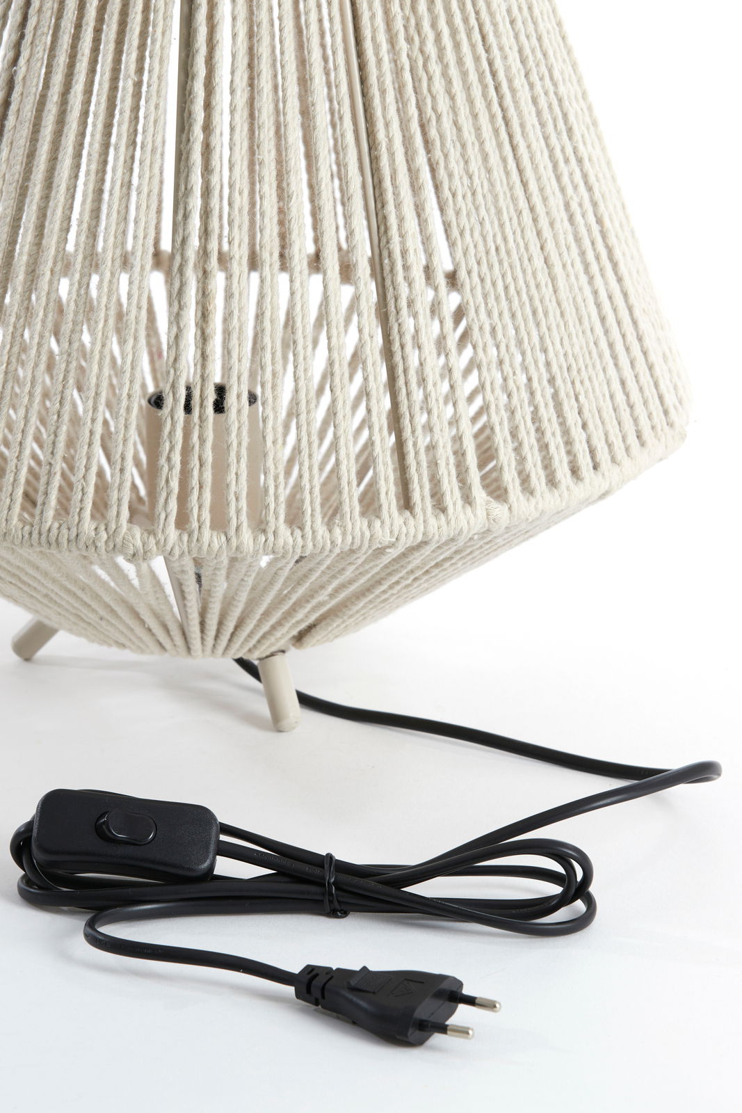 Nahaufnahme einer Tischleuchte mit einem geflochtenen, cremefarbenen Lampenschirm und einem schwarzen Kabel mit Schalter, seitliche Perspektive.