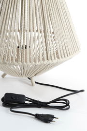 Nahaufnahme einer Tischleuchte mit einem geflochtenen, cremefarbenen Lampenschirm und einem schwarzen Kabel mit Schalter, seitliche Perspektive.