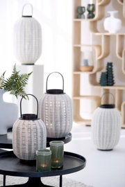 Vooraanzicht op een stijlvolle set witte, ovaalvormige lantaarns met geweven structuur en zwarte metalen hengsels in een modern interieur.