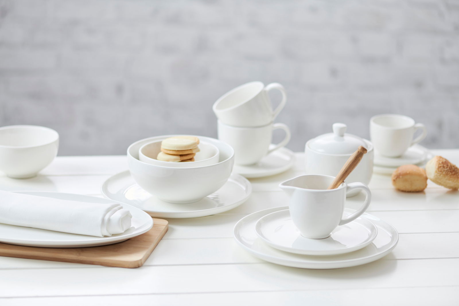 Ritzenhoff & Breker Espressountertasse SKAGEN Elegante Espressountertasse Skagen 11cm aus weißem Porzellan, präsentiert in einer stilvollen Tischdekoration mit weiteren Geschirrteilen, aus der Vogelperspektive.