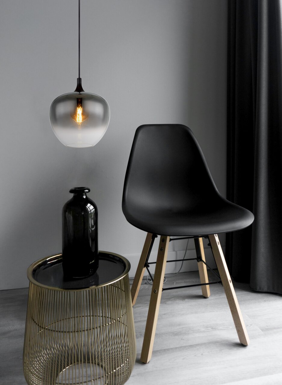 Moderne Hängeleuchte mit rauchgrauem Glas, von der Seite betrachtet, über einem stilvollen Tisch und Stuhl in einem eleganten Raum.