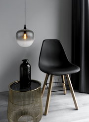 Moderne Hängeleuchte mit rauchgrauem Glas, von der Seite betrachtet, über einem stilvollen Tisch und Stuhl in einem eleganten Raum.