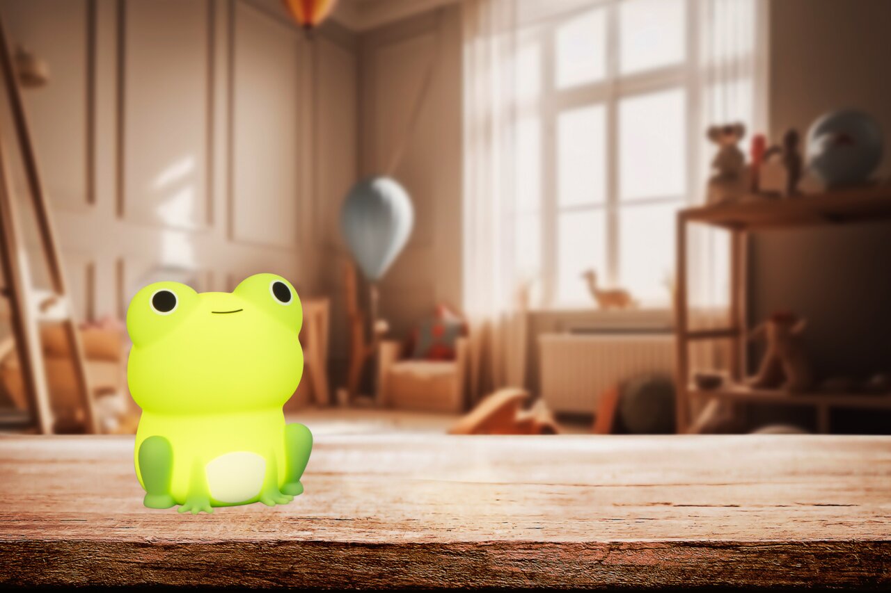 Frontalansicht eines leuchtenden, grünen Frosch-Akku-Nachtlichts auf einem Holztisch in einem gemütlichen Kinderzimmer.