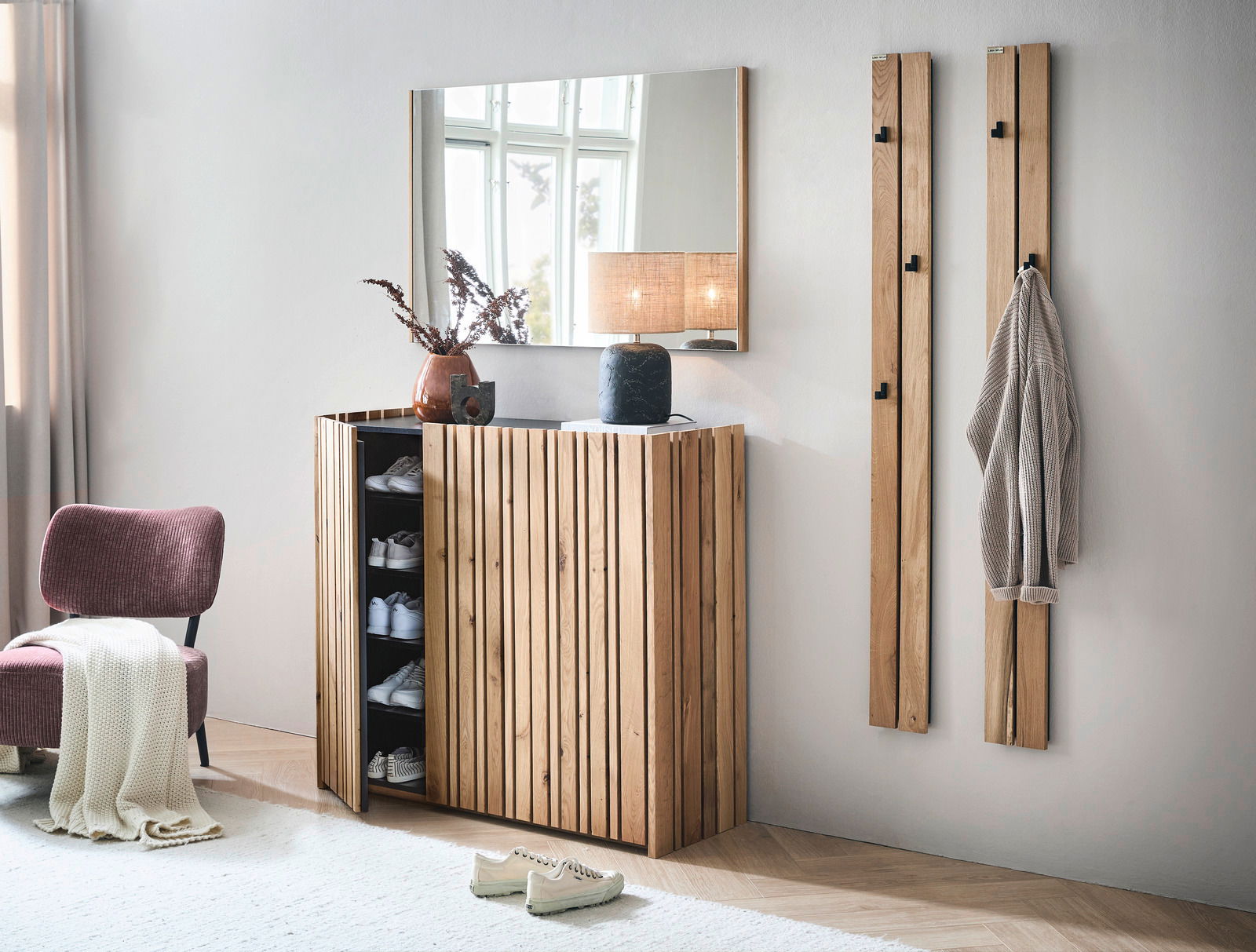 Moderner Eingangsbereich mit einem XL-Schuhschrank aus Holz, einem Spiegel darüber und zwei Garderobenpaneelen an der Wand. Perspektive: Frontalansicht.