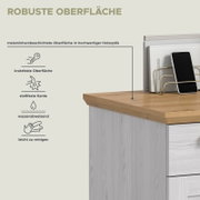 Schräg von oben fotografierte Detailansicht einer Kommode mit melaminharzbeschichteter, holzoptischer Deckplatte; zeigt robuste, kratz- und stoßfeste sowie wasserabweisende, leicht zu reinigende Oberfläche mit Smartphone und Zeitschriftenhalter.