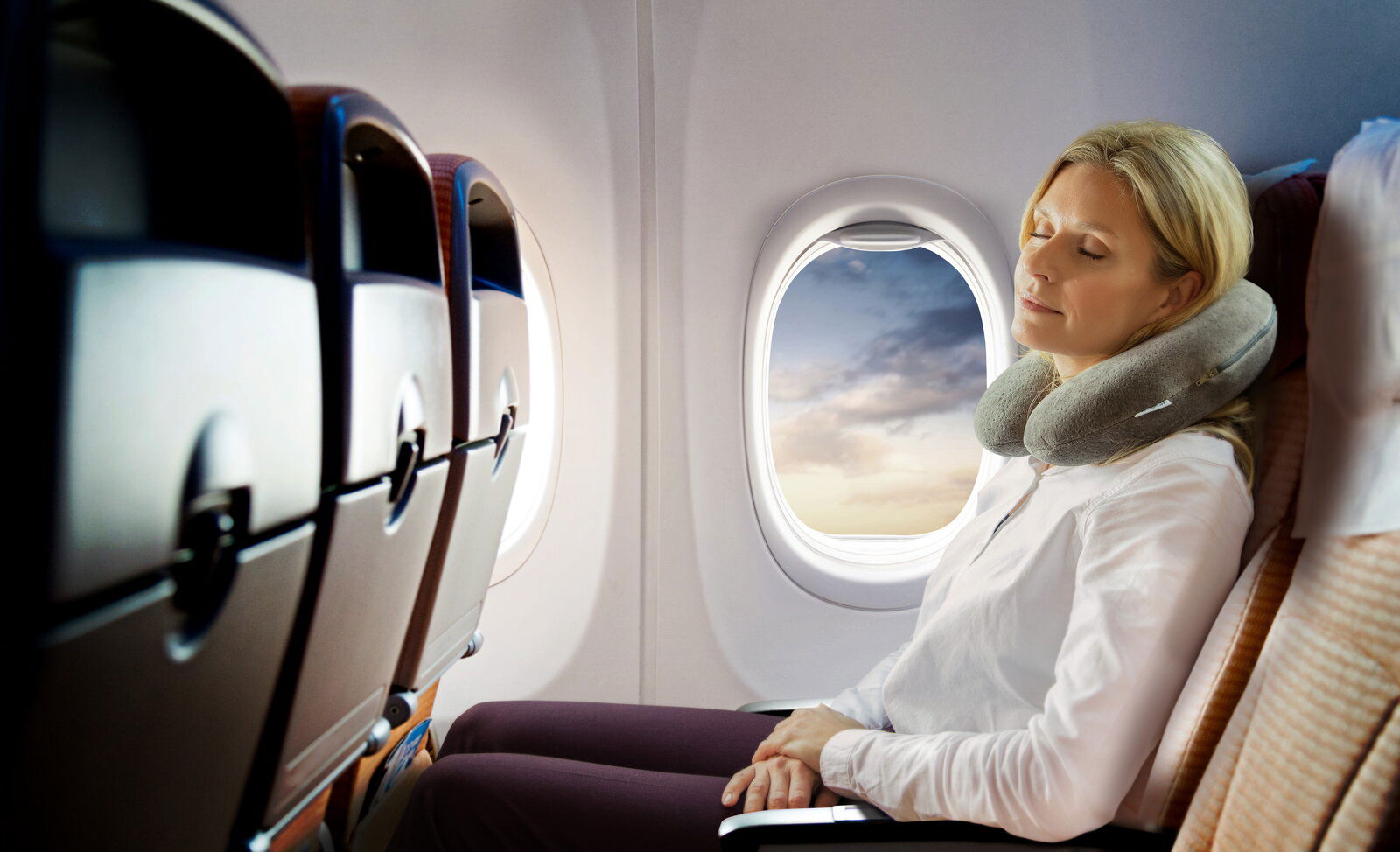 Tempur Transitkissen Frau entspannt mit Tempur Transitkissen im Flugzeug, seitliche Perspektive