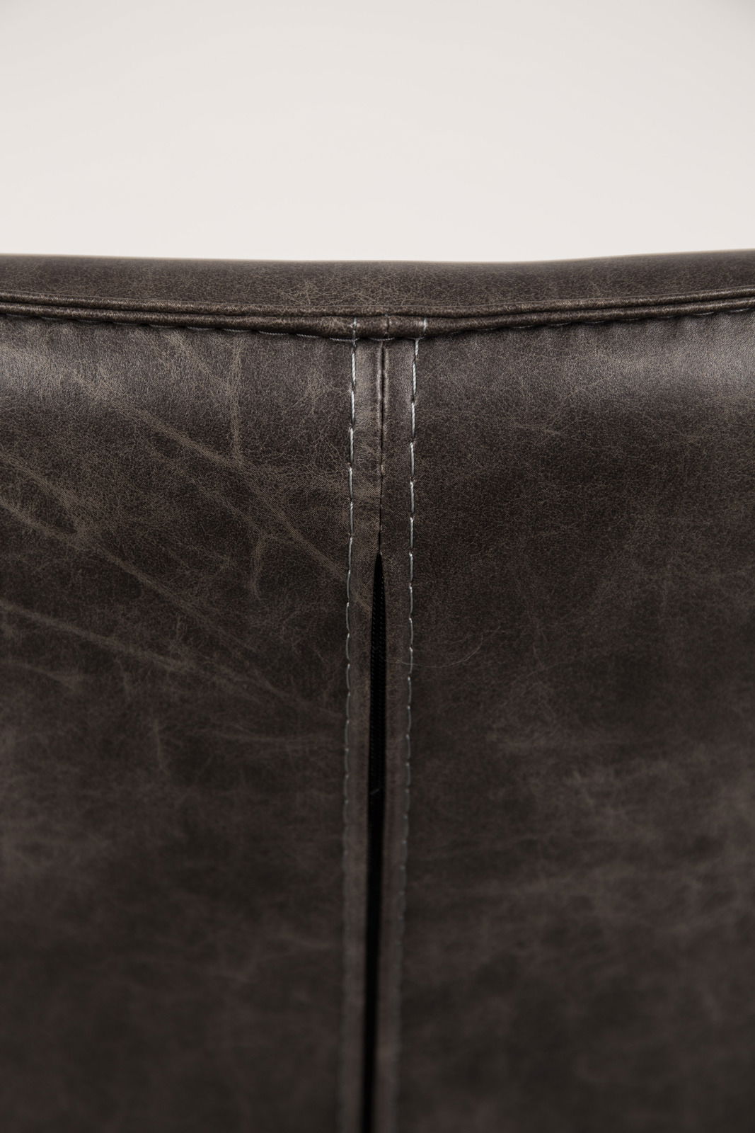 Rückansicht eines Sessels mit dunkelbraunem Lederbezug und sichtbarer Naht.