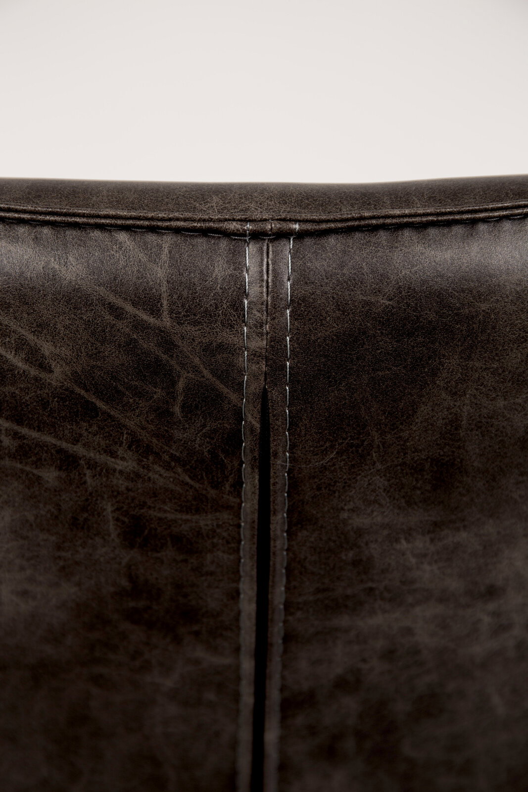 Rückansicht eines Sessels mit dunkelbraunem Lederbezug und sichtbarer Naht.