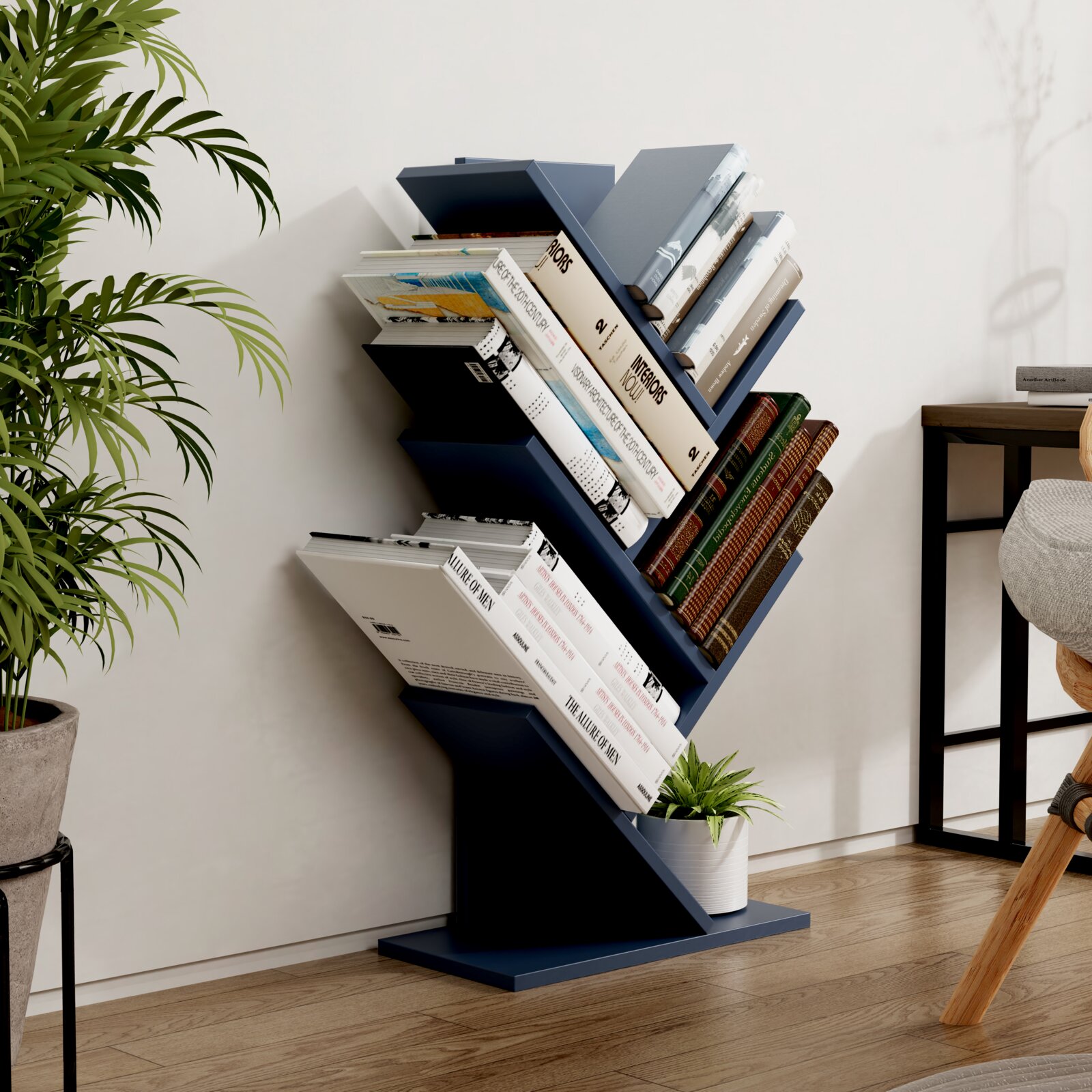Modernes, dunkelblaues Zickzack-Bücherregal/Standregal mit schrägen Ablagen, gefüllt mit Büchern und kleinem Blumentopf, im Wohnzimmer neben einer Pflanze; Perspektive: leicht schräg von vorne.