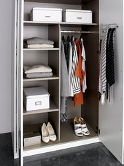 Offener Drehtürenschrank mit sechs Türen, gefüllt mit Kleidung, Schuhen und Aufbewahrungsboxen, aus der Frontalperspektive.