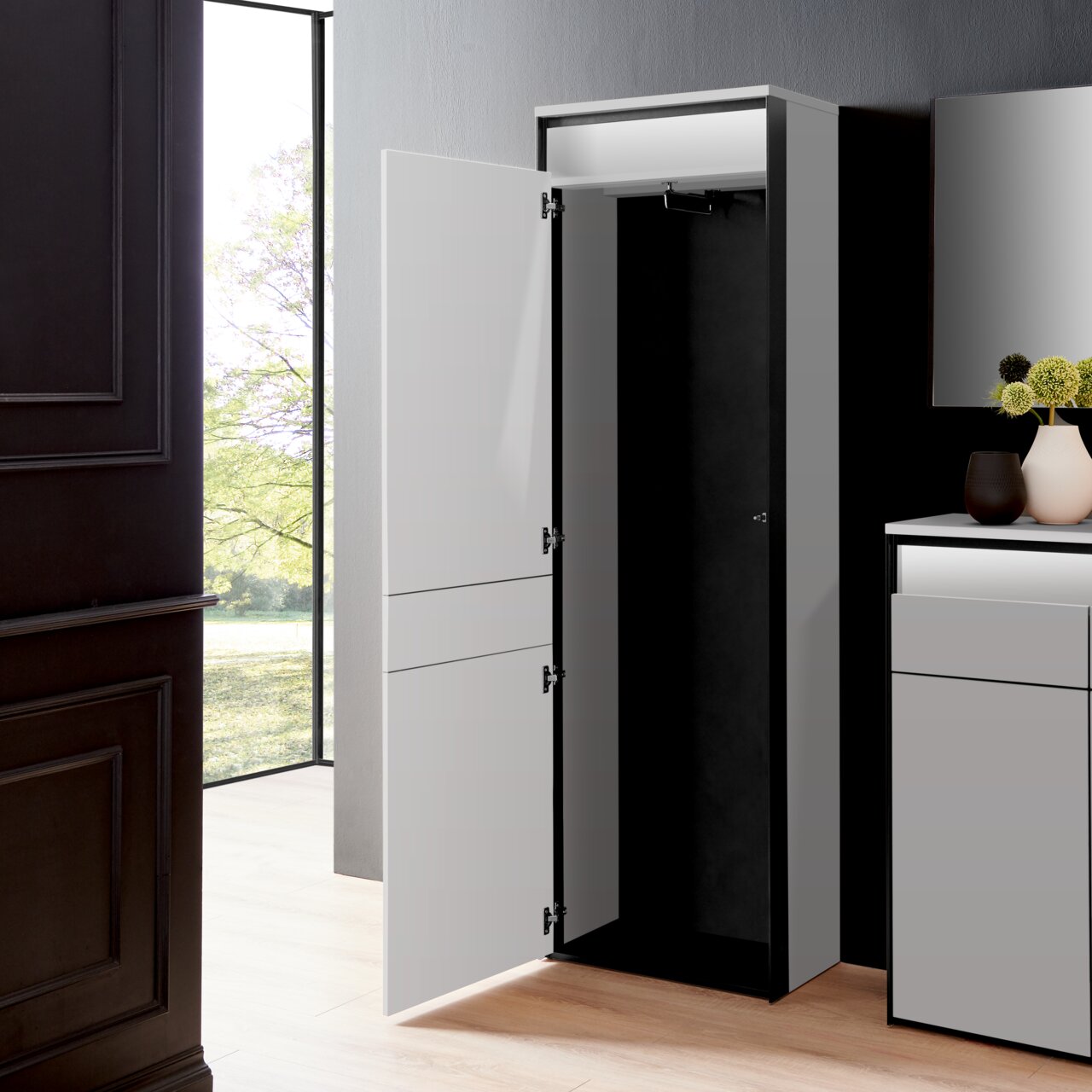 Moderner Garderobenschrank in einem eleganten Raum, mit geöffneter Tür, die den Innenraum zeigt. Perspektive von vorne.