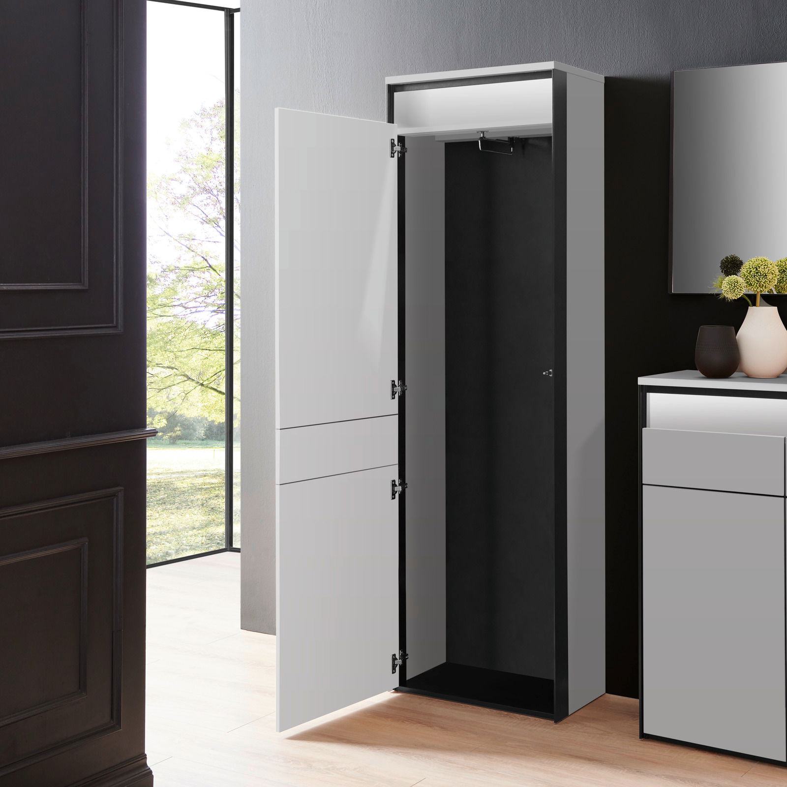 Moderner Garderobenschrank in einem eleganten Raum, mit geöffneter Tür, die den Innenraum zeigt. Perspektive von vorne.