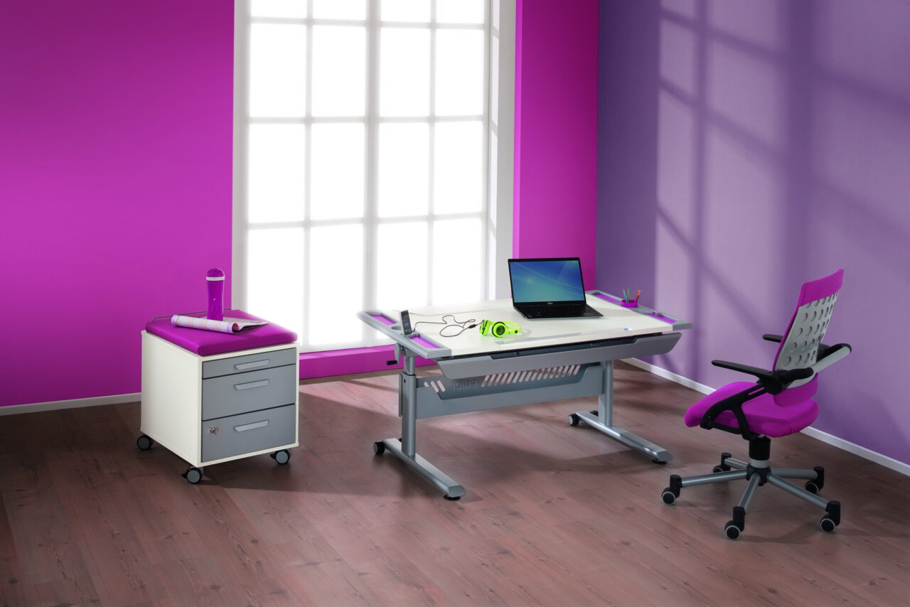Paidi Schreibtisch TABLO Moderner Schreibtisch in einem hellen Raum mit pinken und lila Wänden, ausgestattet mit einem Laptop, Kopfhörern und Schreibutensilien. Perspektive: seitliche Ansicht.