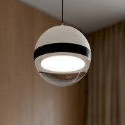 Moderne, kugelförmige Pendelleuchte in Weiß mit schwarzem Ring und leuchtender, runder LED-Unterseite, fotografiert aus leichter Untersicht in einem Innenraum