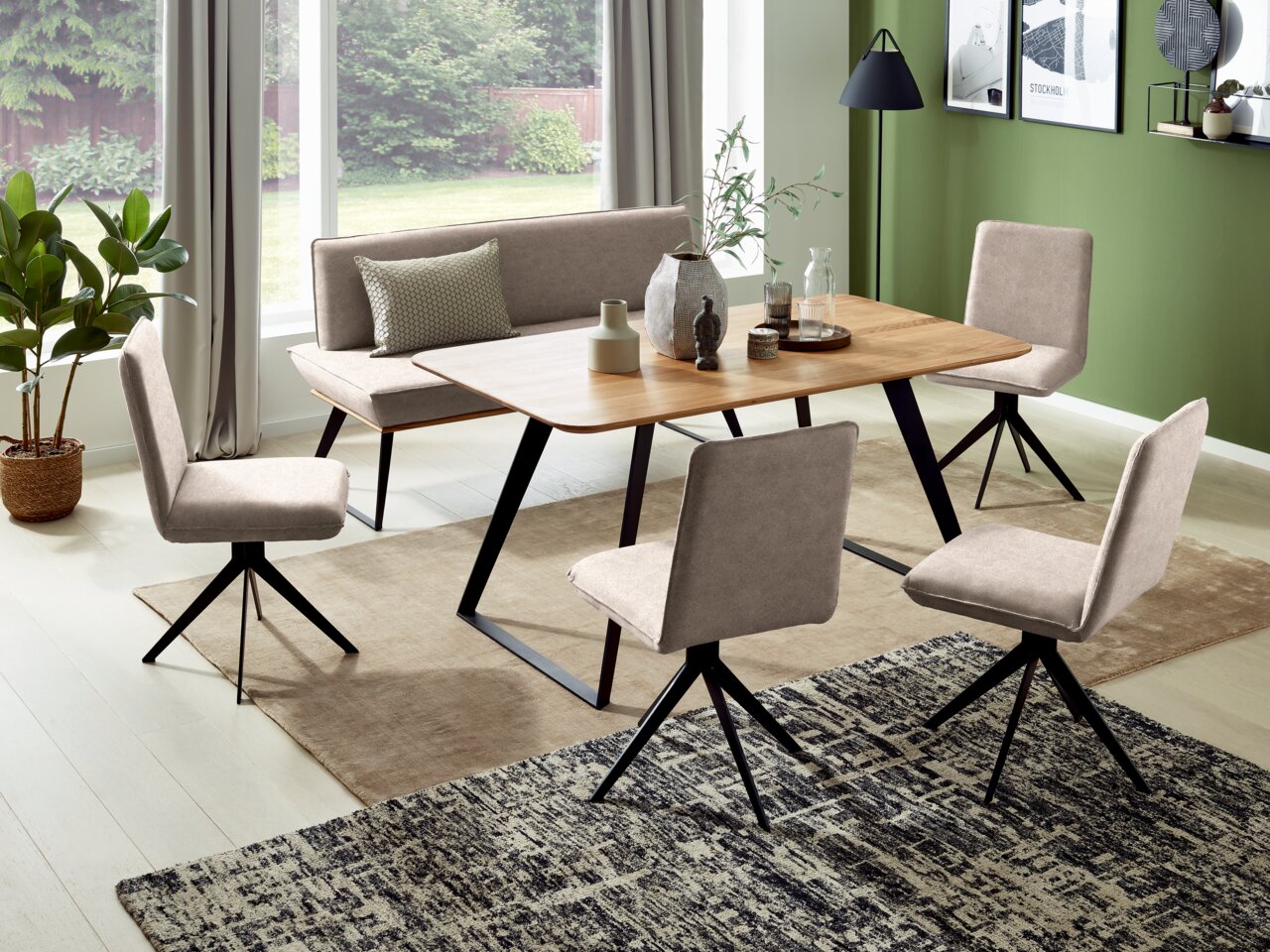 Esszimmer mit modernem Tisch und Bank in Holzoptik, umgeben von vier gepolsterten Stühlen. Die Perspektive zeigt den Raum von der Seite mit Blick auf die Fensterfront.