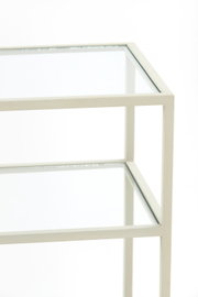 Close-up van een consoletafel met glazen bladen en een wit metalen frame, gezien vanaf de zijkant