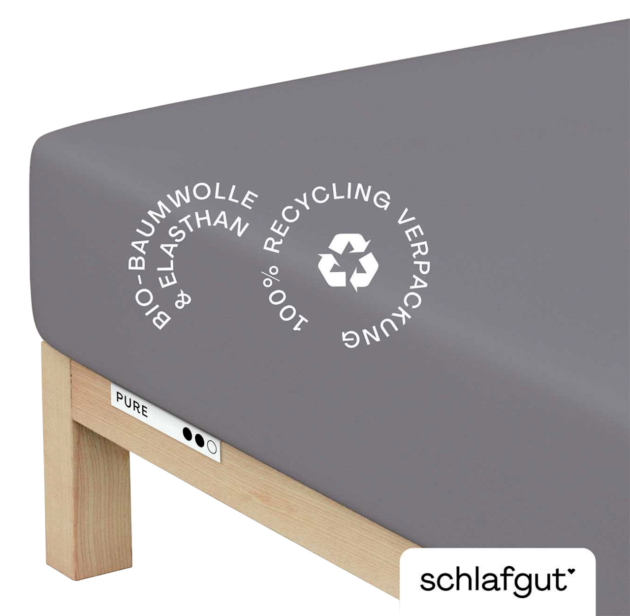 schlafgut Spannbettlaken XL 128 Pure Graues Spannbettlaken aus Bio-Baumwolle und Elasthan auf einem Bett, mit Recycling-Symbol, seitliche Perspektive