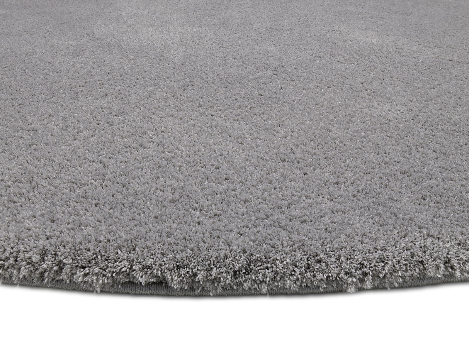 Grauer, runder Teppich mit weicher, flauschiger Oberfläche, Nahaufnahme der Kante.