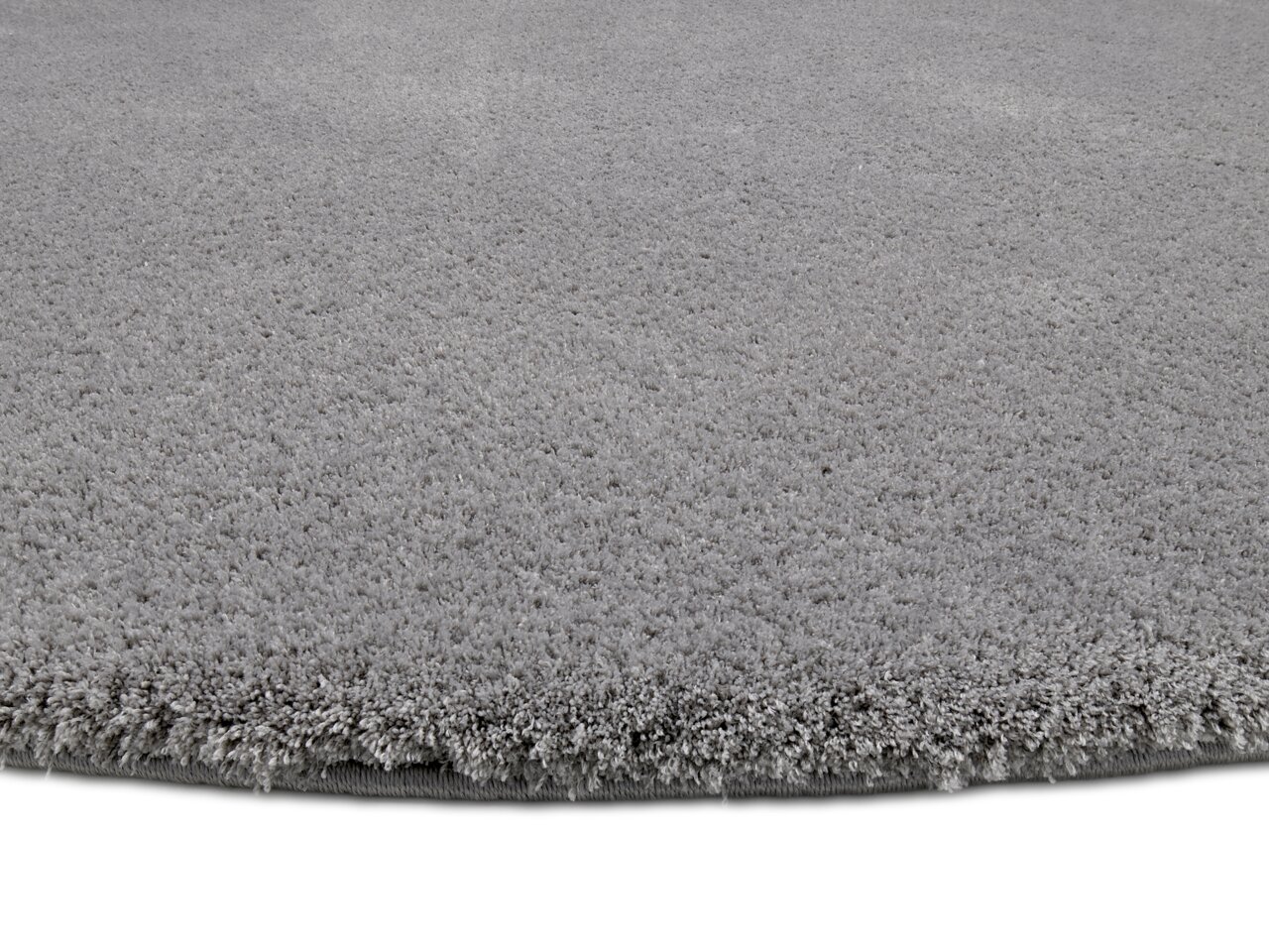 Grauer, runder Teppich mit weicher, flauschiger Oberfläche, Nahaufnahme der Kante.