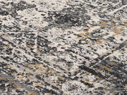 Nahaufnahme eines Designer-Teppichs mit abstraktem Muster in Grau-, Weiß- und Gelbtönen, aus schräger Perspektive fotografiert.