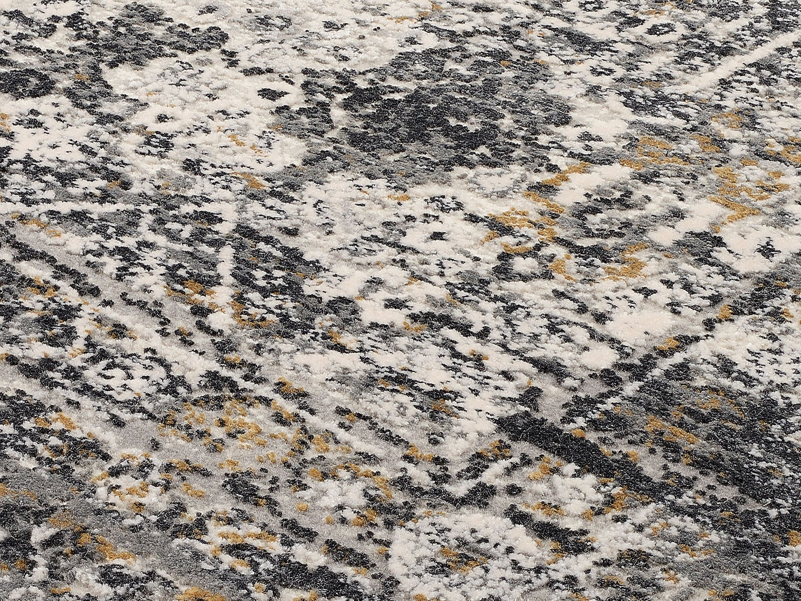Nahaufnahme eines Designer-Teppichs mit abstraktem Muster in Grau-, Weiß- und Gelbtönen, aus schräger Perspektive fotografiert.