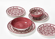 Vogelperspektive auf ein 16-teiliges Tellerset in Burgund mit dekorativen Mustern.