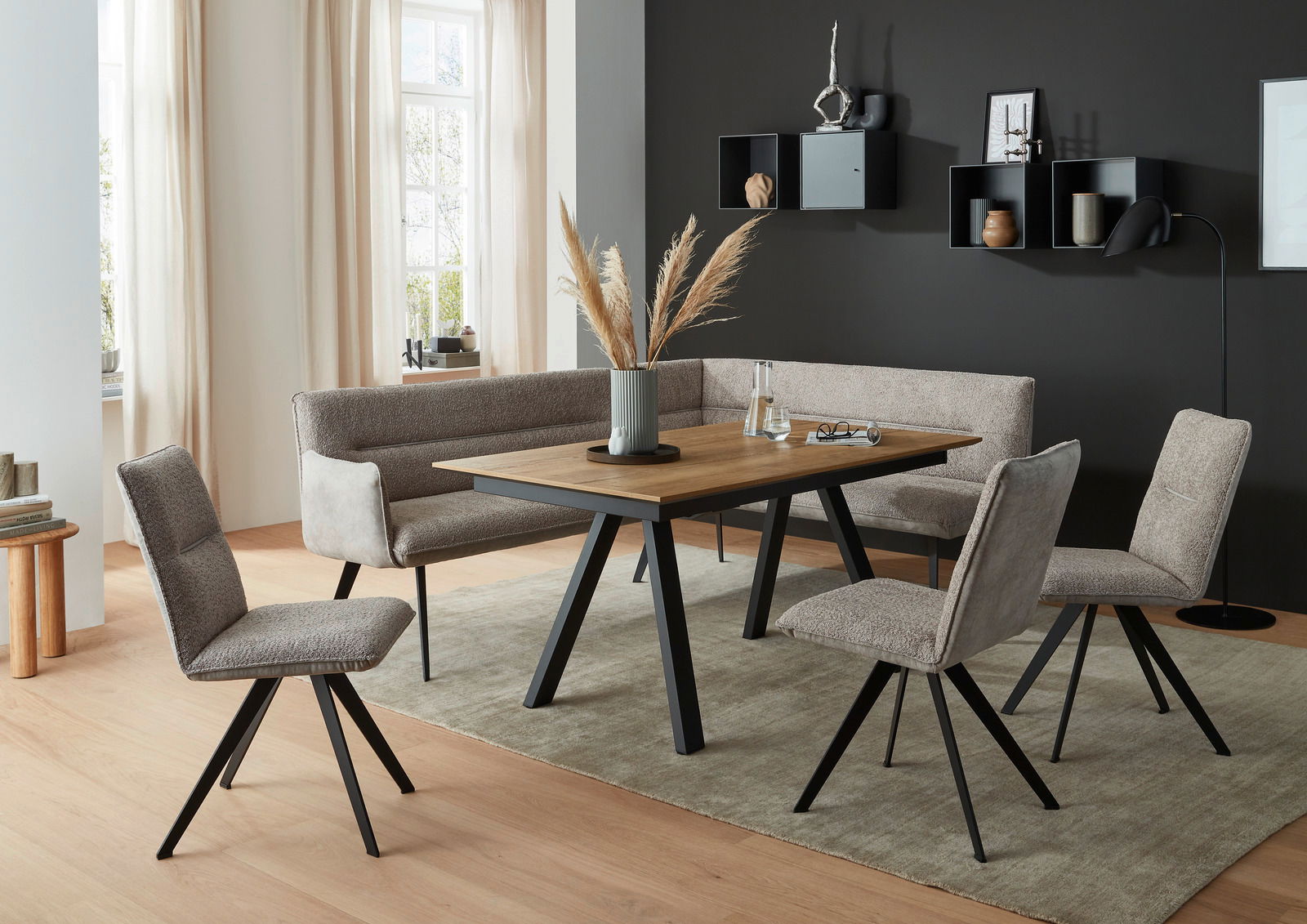 Moderner Esstisch mit Holzplatte und schwarzen Metallbeinen, umgeben von gepolsterten Stühlen und einer Eckbank in einem stilvoll eingerichteten Esszimmer, seitliche Perspektive.