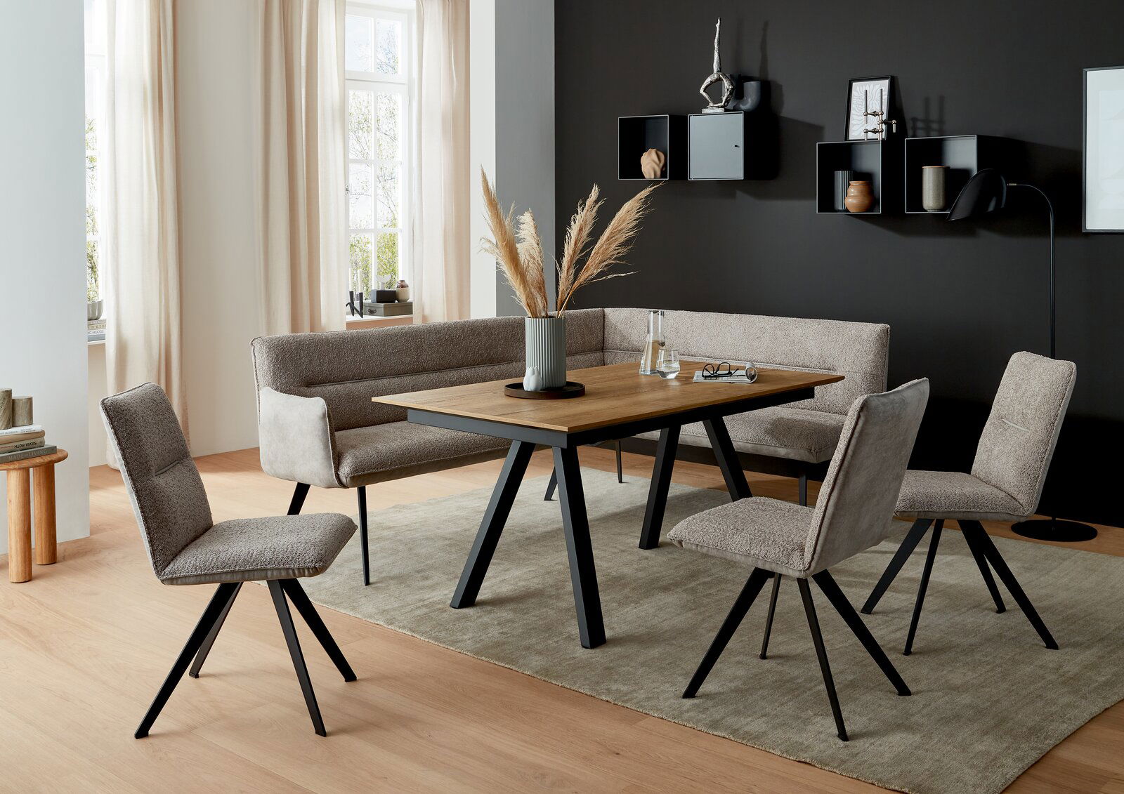 Moderner Esstisch mit Holzplatte und schwarzen Metallbeinen, umgeben von gepolsterten Stühlen und einer Eckbank in einem stilvoll eingerichteten Esszimmer, seitliche Perspektive.