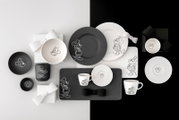 Schwarz-weißes Disney-Micky-und-Minnie-Maus-Geschirrset mit Tellern, Tassen, Schalen, Untertassen und Servierplatte, flach von oben (Top-Down) auf zweifarbigem Hintergrund arrangiert