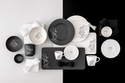 Schwarz-weißes Disney-Micky-und-Minnie-Maus-Geschirrset mit Tellern, Tassen, Schalen, Untertassen und Servierplatte, flach von oben (Top-Down) auf zweifarbigem Hintergrund arrangiert
