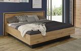 Modernes Doppelbett aus Holz mit gemütlicher Bettwäsche, seitliche Perspektive