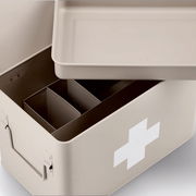 Beige Medizinbox mit abnehmbarem Deckel und Fächern, von oben betrachtet, mit weißem Kreuz auf der Seite.