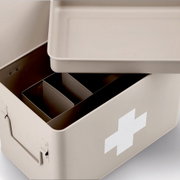 Beige Medizinbox mit abnehmbarem Deckel und Fächern, von oben betrachtet, mit weißem Kreuz auf der Seite.