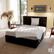 Modernes Schlafzimmer mit einem eleganten, schwarzen Bett und einem Spessarttraum Kissen GOLD in der Größe 80x80cm, seitliche Perspektive.