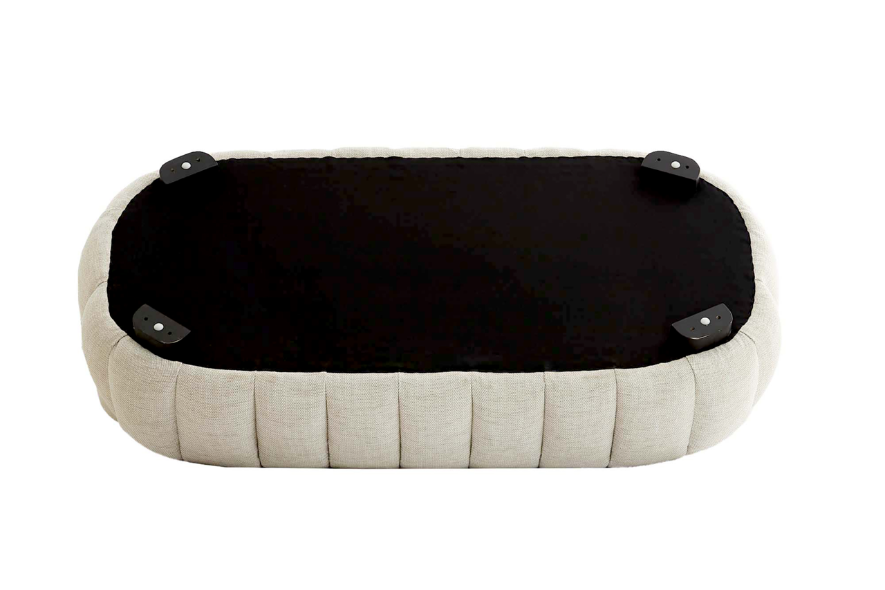Unterseite einer Couch in ovaler Form mit beigem Stoffbezug und schwarzen Füßen, Ansicht von unten.