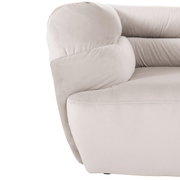Close-up van een beige grote bank met zachte bekleding en afgeronde armleuningen, gezien vanaf de zijkant.