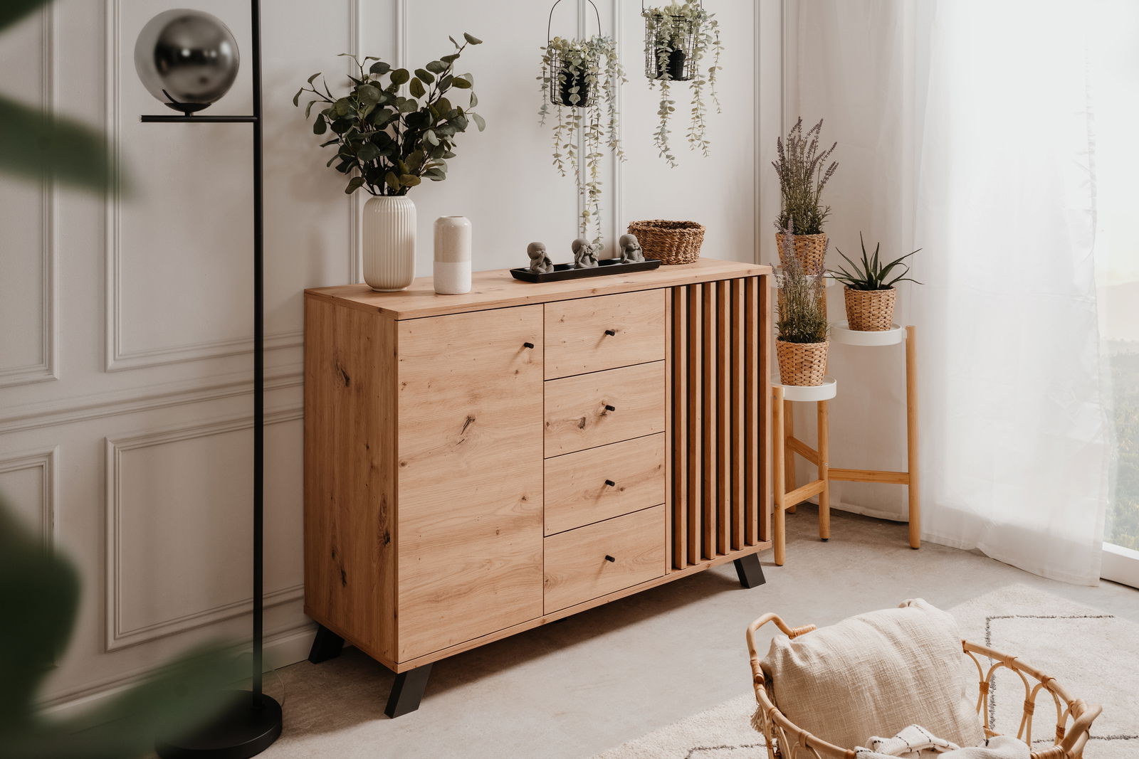 Holzkommode mit Schubladen und Lamellentür, dekoriert mit Pflanzen und Accessoires, seitliche Perspektive